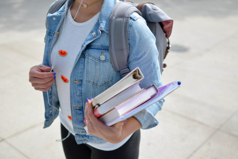 student wearing a backpack and holding books
